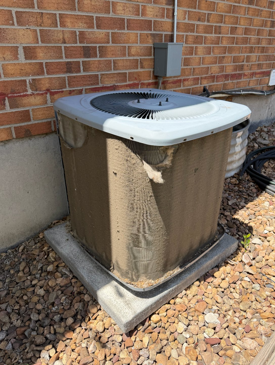 Dirty condenser unit against brick wall